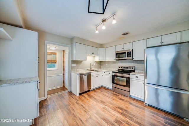 4229 Hillbrook Dr, Louisville, KY 40220 - kitchen with appliances with stainless steel finishes, decorative backsplash, white cabinets, light wood finished floors, and light stone countertops