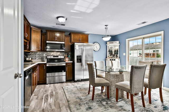 120 Spring Leaf Ct, Shelbyville, KY 40065 - kitchen featuring appliances with stainless steel finishes, light wood-style flooring, backsplash, light countertops, and hanging light fixtures