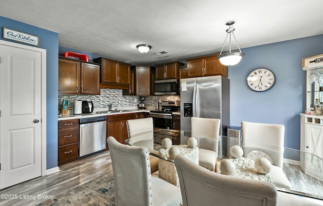 120 Spring Leaf Ct, Shelbyville, KY 40065 - kitchen featuring appliances with stainless steel finishes, light wood-type flooring, light countertops, tasteful backsplash, and pendant lighting