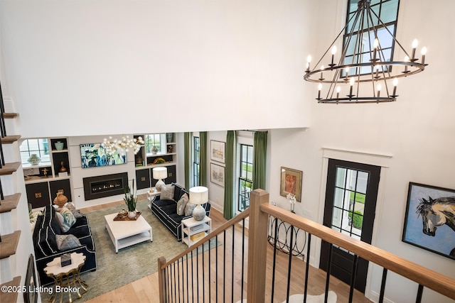 11403 River Beauty Loop, Prospect, KY 40059 - living room featuring a chandelier, a high ceiling, wood finished floors, and a warm lit fireplace