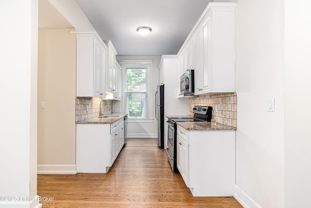 1629 S 3rd St Apt 102, Louisville, KY 40208 - kitchen featuring stainless steel appliances, backsplash, white cabinets, and light wood-type flooring