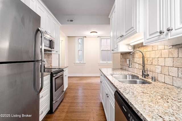 1629 S 3rd St Apt 102, Louisville, KY 40208 - kitchen featuring appliances with stainless steel finishes, white cabinets, decorative backsplash, and wood finished floors