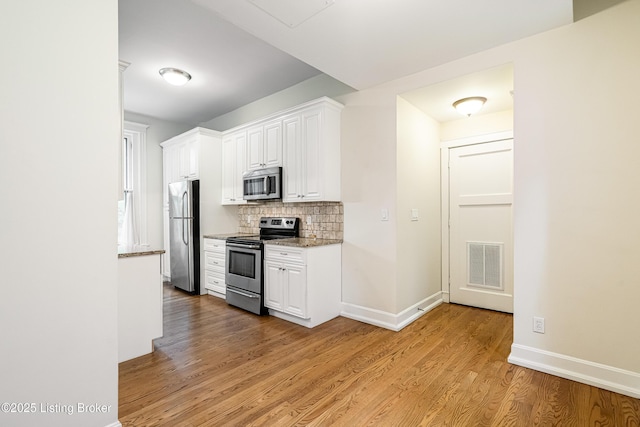 1629 S 3rd St Apt 102, Louisville, KY 40208 - kitchen with stainless steel appliances, light wood-type flooring, decorative backsplash, white cabinetry, and light stone counters