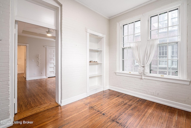 1629 S 3rd St Apt 102, Louisville, KY 40208 - unfurnished room featuring hardwood / wood-style floors, brick wall, built in shelves, ornamental molding, and a ceiling fan