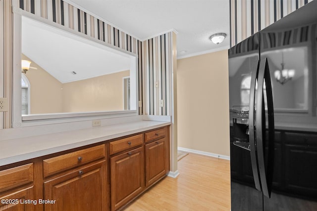 8001 Port Royal Ct, Louisville, KY 40291 - kitchen with black fridge, brown cabinets, light countertops, ornamental molding, and light wood finished floors
