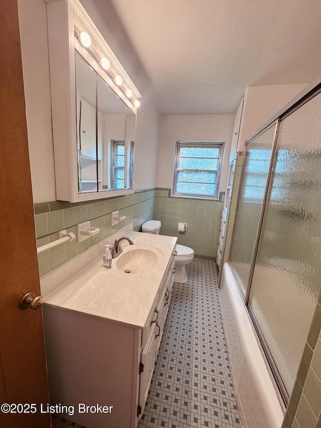 5019 S Wilson Rd, Elizabethtown, KY 42701 - bathroom featuring vanity, a wainscoted wall, tile walls, tile patterned floors, and shower / bath combination with glass door