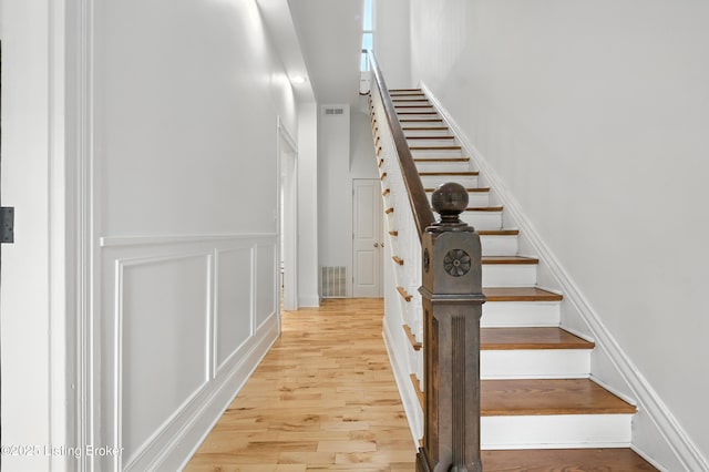 143 State St, Louisville, KY 40206 - stairs featuring wood finished floors, a wainscoted wall, and a decorative wall