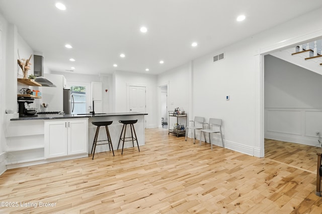 143 State St, Louisville, KY 40206 - kitchen with open shelves, dark countertops, ventilation hood, light wood finished floors, and a peninsula