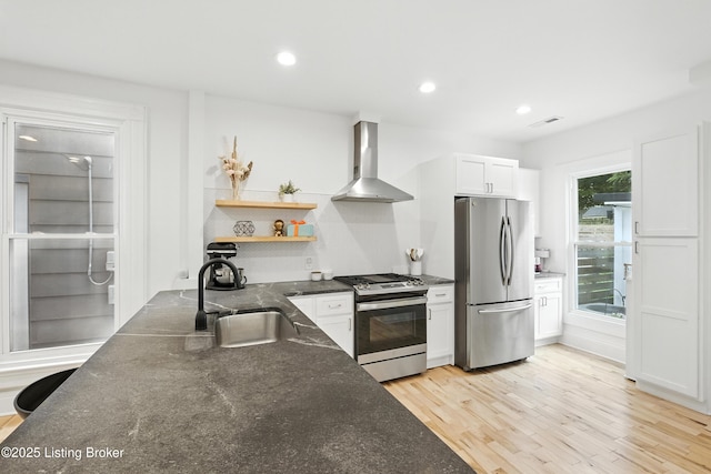 143 State St, Louisville, KY 40206 - kitchen featuring appliances with stainless steel finishes, wall chimney exhaust hood, open shelves, white cabinets, and light wood-style flooring