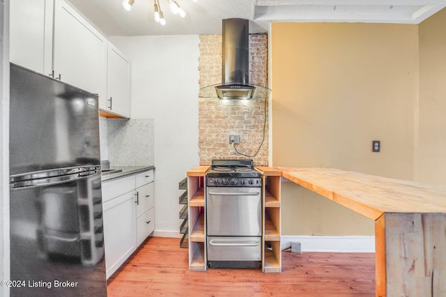 1131 S Brook St Apt 3, Louisville, KY 40203 - kitchen featuring stainless steel range with gas stovetop, freestanding refrigerator, wall chimney exhaust hood, and light wood-style floors