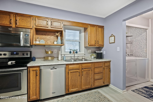 8433 Chase Rd, Louisville, KY 40258 - kitchen with appliances with stainless steel finishes, washing machine and clothes dryer, brown cabinetry, light wood-style floors, and crown molding