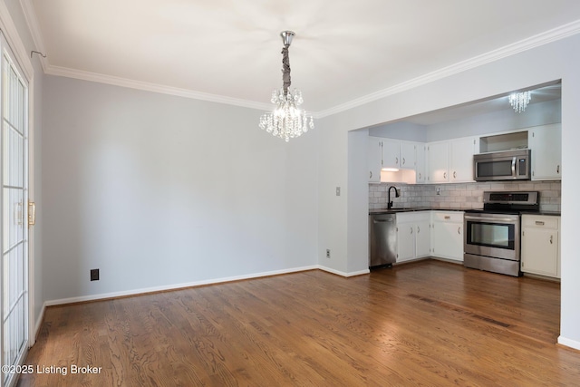 6503 Deep Creek Dr Unit 1, Prospect, KY 40059 - kitchen featuring appliances with stainless steel finishes, a chandelier, dark countertops, crown molding, and tasteful backsplash