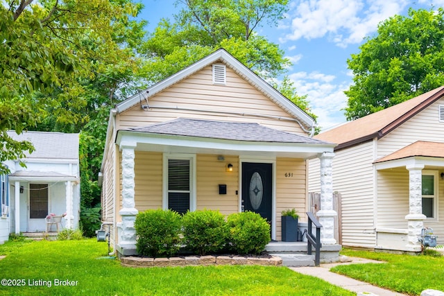 631 Lynn St, Louisville, KY 40217 - shotgun-style home with covered porch, a front lawn, and roof with shingles