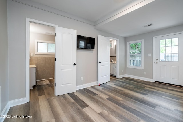 631 Lynn St, Louisville, KY 40217 - unfurnished bedroom with multiple windows, dark wood-style floors, and ensuite bath