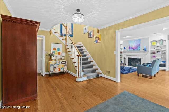 5612 Apache Rd, Louisville, KY 40207 - staircase with wood finished floors, ornamental molding, a chandelier, a fireplace, and built in shelves