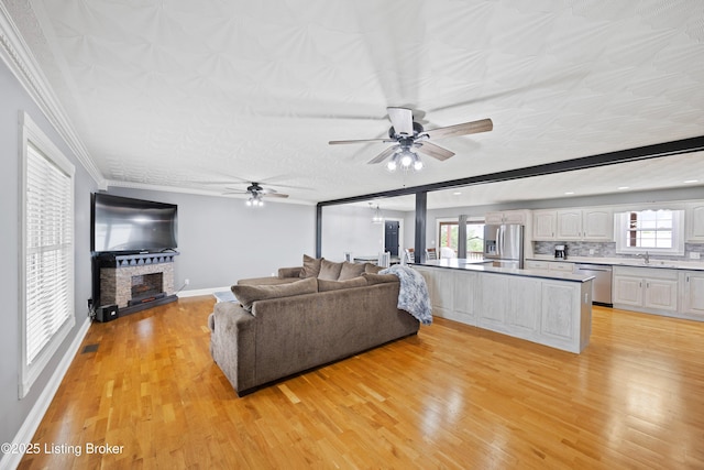 192 Loretto Rd, Springfield, KY 40069 - living area featuring a ceiling fan, light wood-type flooring, a fireplace with raised hearth, and crown molding