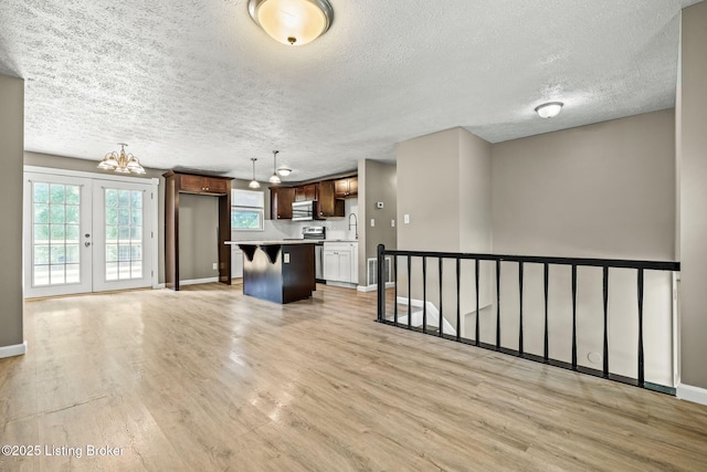 3619 Endeavor Way, Louisville, KY 40219 - unfurnished living room featuring light wood-type flooring, a textured ceiling, a chandelier, and french doors