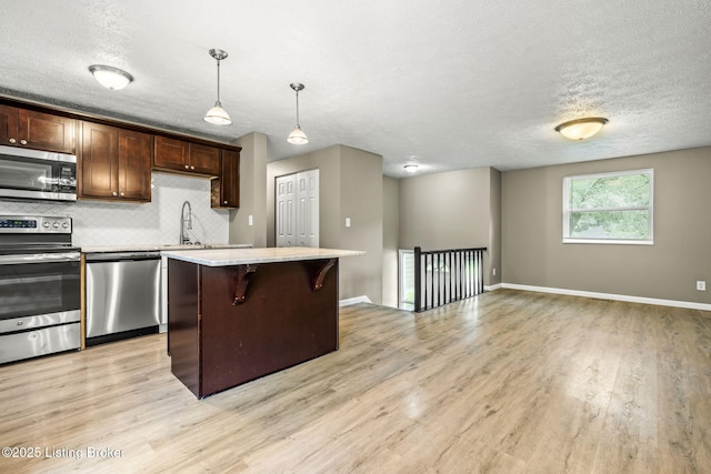 3619 Endeavor Way, Louisville, KY 40219 - kitchen featuring appliances with stainless steel finishes, light wood-style flooring, light countertops, a kitchen island, and a textured ceiling