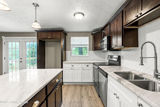 3619 Endeavor Way, Louisville, KY 40219 - kitchen featuring appliances with stainless steel finishes, dark brown cabinets, light wood-style flooring, backsplash, and pendant lighting