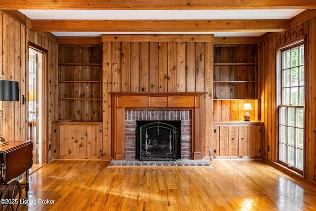 3920 Elfin Ave, Louisville, KY 40207 - unfurnished living room featuring wood walls, beamed ceiling, wood finished floors, built in features, and a brick fireplace