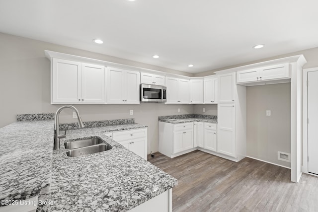3020 Thorntree Ln, Lawrenceburg, KY 40342 - kitchen with stainless steel microwave, light stone countertops, light wood-type flooring, recessed lighting, and white cabinets