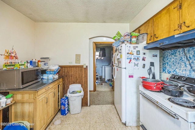911 N Main St, Barbourville, KY 40906 - kitchen featuring white appliances, under cabinet range hood, arched walkways, a wainscoted wall, and brown cabinetry