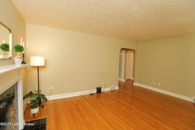 3303 Eagle Pass, Louisville, KY 40213 - unfurnished living room featuring a fireplace, arched walkways, wood finished floors, and a textured ceiling