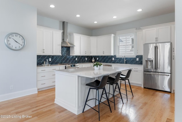 6113 St Bernadette Ave, Prospect, KY 40059 - kitchen featuring appliances with stainless steel finishes, wall chimney range hood, a breakfast bar area, white cabinetry, and recessed lighting