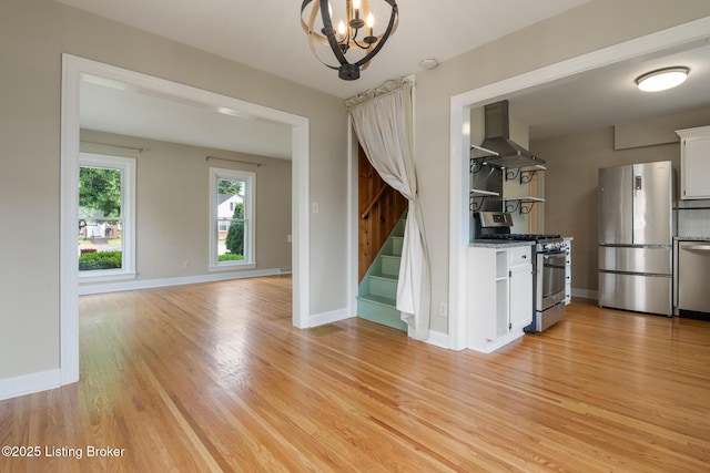 1005 Rosemary Dr, Louisville, KY 40213 - kitchen with wall chimney range hood, appliances with stainless steel finishes, light wood-style floors, a chandelier, and white cabinetry