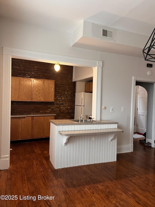 1308 S 2nd St, Louisville, KY 40208 - kitchen with freestanding refrigerator, dark wood finished floors, brown cabinets, and a kitchen breakfast bar