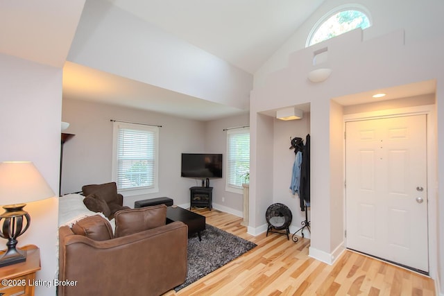 129 E Park Pl, Jeffersonville, IN 47130 - living room featuring light wood-style floors, a wood stove, and high vaulted ceiling