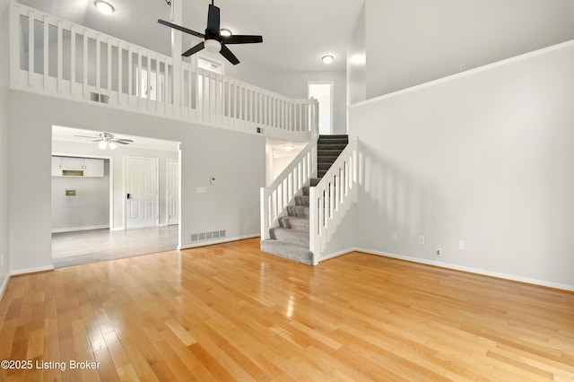 11411 Catalpa View Ct, Louisville, KY 40299 - unfurnished living room with ceiling fan, wood finished floors, stairway, and a towering ceiling