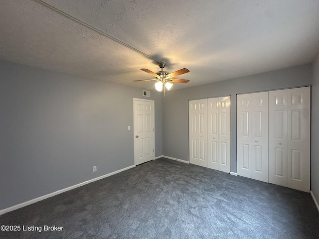 7070 Wildwood Cir Unit 154, Louisville, KY 40291 - unfurnished bedroom with two closets, dark colored carpet, ceiling fan, and a textured ceiling