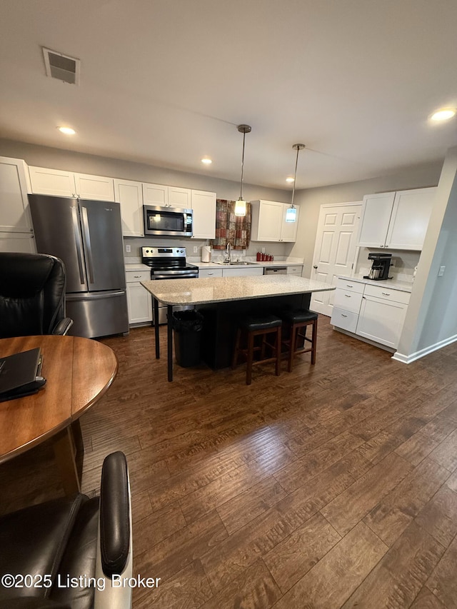 5620 Carolyn Way, Louisville, KY 40219 - kitchen with appliances with stainless steel finishes, dark wood finished floors, white cabinets, a kitchen breakfast bar, and recessed lighting
