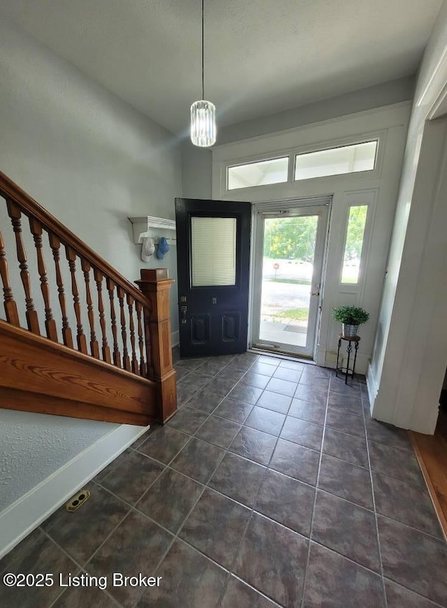 216 6th St, Carrollton, KY 41008 - entrance foyer with dark tile patterned floors, stairs, and a chandelier