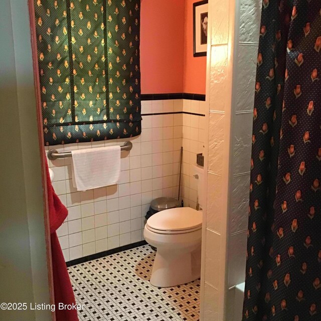 1852 Cypress St, Louisville, KY 40210 - bathroom with wainscoting, a shower with shower curtain, tile walls, and tile patterned floors