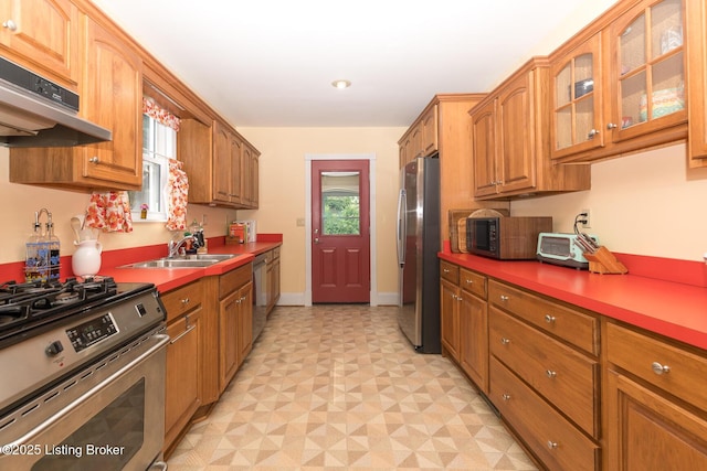 2309 Payne St, Louisville, KY 40206 - kitchen featuring appliances with stainless steel finishes, under cabinet range hood, light flooring, brown cabinets, and glass insert cabinets