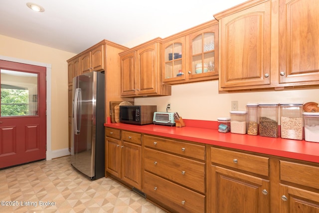 2309 Payne St, Louisville, KY 40206 - kitchen featuring freestanding refrigerator, black microwave, light floors, glass insert cabinets, and brown cabinets