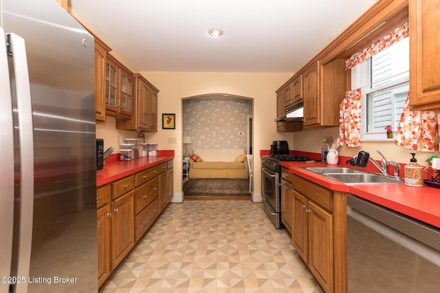 2309 Payne St, Louisville, KY 40206 - kitchen with stainless steel appliances, light flooring, under cabinet range hood, glass insert cabinets, and brown cabinets