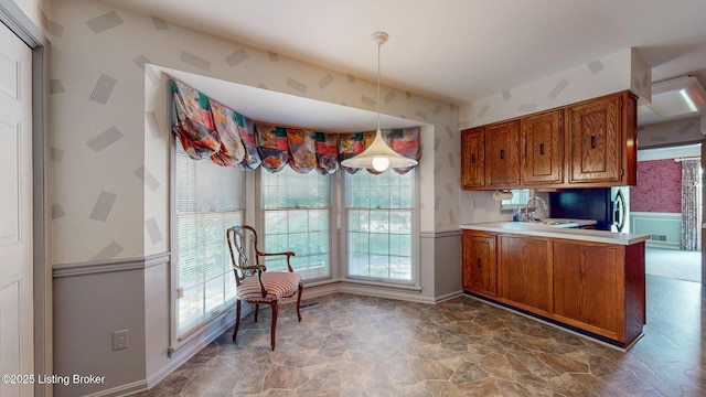 1810 Bainbridge Row Dr, Louisville, KY 40207 - kitchen featuring wallpapered walls, brown cabinetry, a wainscoted wall, hanging light fixtures, and light countertops