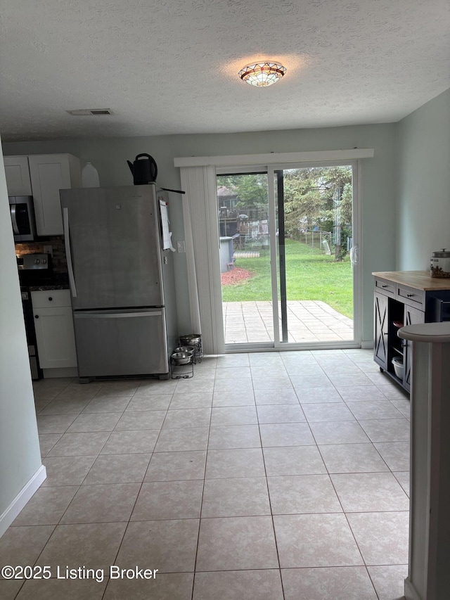 11902 Queen Annes Ct, Louisville, KY 40245 - kitchen featuring stainless steel appliances, a textured ceiling, light tile patterned floors, backsplash, and white cabinetry