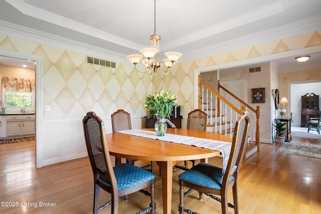 11731 Paramont Way, Prospect, KY 40059 - dining area featuring a chandelier, crown molding, wallpapered walls, light wood-style floors, and stairs