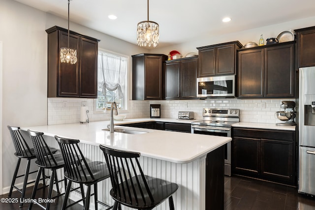18007 Ellerslie Dr, Louisville, KY 40245 - kitchen with appliances with stainless steel finishes, light countertops, a breakfast bar area, dark wood finished floors, and recessed lighting