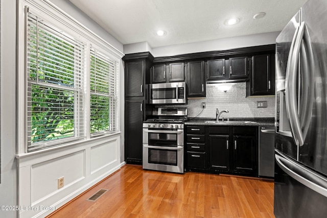 10505 Kovats Ct, Louisville, KY 40223 - kitchen featuring stainless steel appliances, dark cabinets, dark countertops, decorative backsplash, and light wood-type flooring
