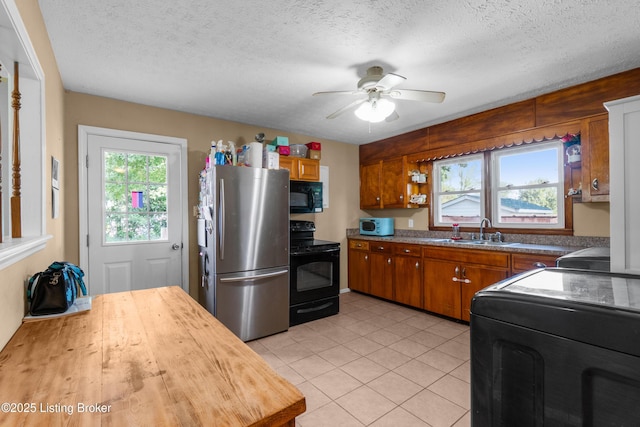 1255 Holy Cross Rd, Loretto, KY 40037 - kitchen featuring black appliances, brown cabinetry, ceiling fan, wood counters, and light tile patterned floors