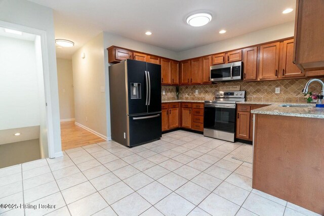 9829 Galene Dr, Jeffersontown, KY 40299 - kitchen featuring stainless steel appliances, brown cabinets, tasteful backsplash, light stone counters, and recessed lighting