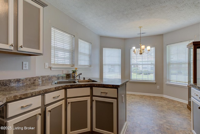 6813 Casey Pl, Louisville, KY 40229 - kitchen featuring dark countertops, decorative light fixtures, a chandelier, a peninsula, and a textured ceiling