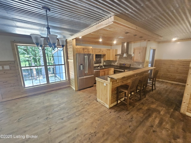 409 Woodhaven Ln, Leitchfield, KY 42754 - kitchen featuring stainless steel appliances, wall chimney range hood, light brown cabinetry, a wainscoted wall, and wood walls