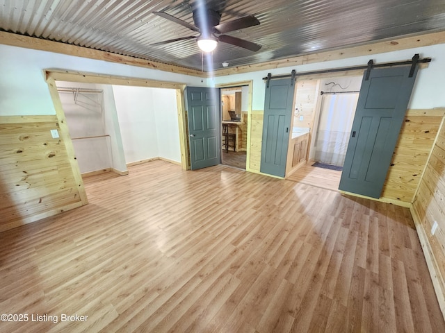 409 Woodhaven Ln, Leitchfield, KY 42754 - unfurnished bedroom with a barn door, light wood finished floors, ensuite bath, and wood walls