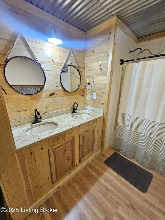 409 Woodhaven Ln, Leitchfield, KY 42754 - bathroom featuring wood walls, double vanity, wood finished floors, and curtained shower